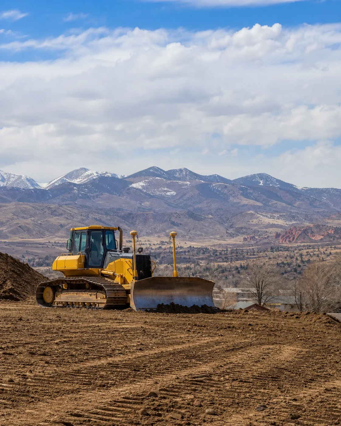 Wheel loader on a cleared hillside lot above the Denver metro
