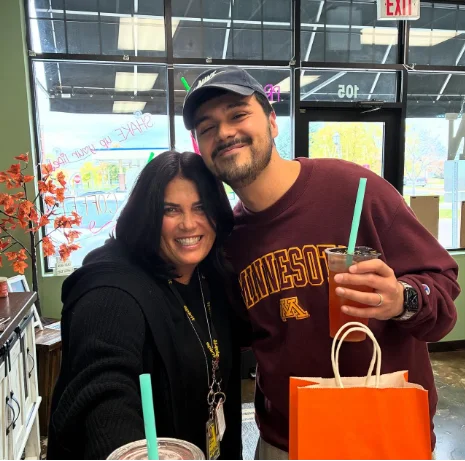 Two customers smiling with drinks and a takeout bag at Restore Nutrition