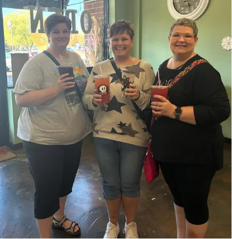 Three friends holding drinks together inside Restore Nutrition in Plymouth, MN