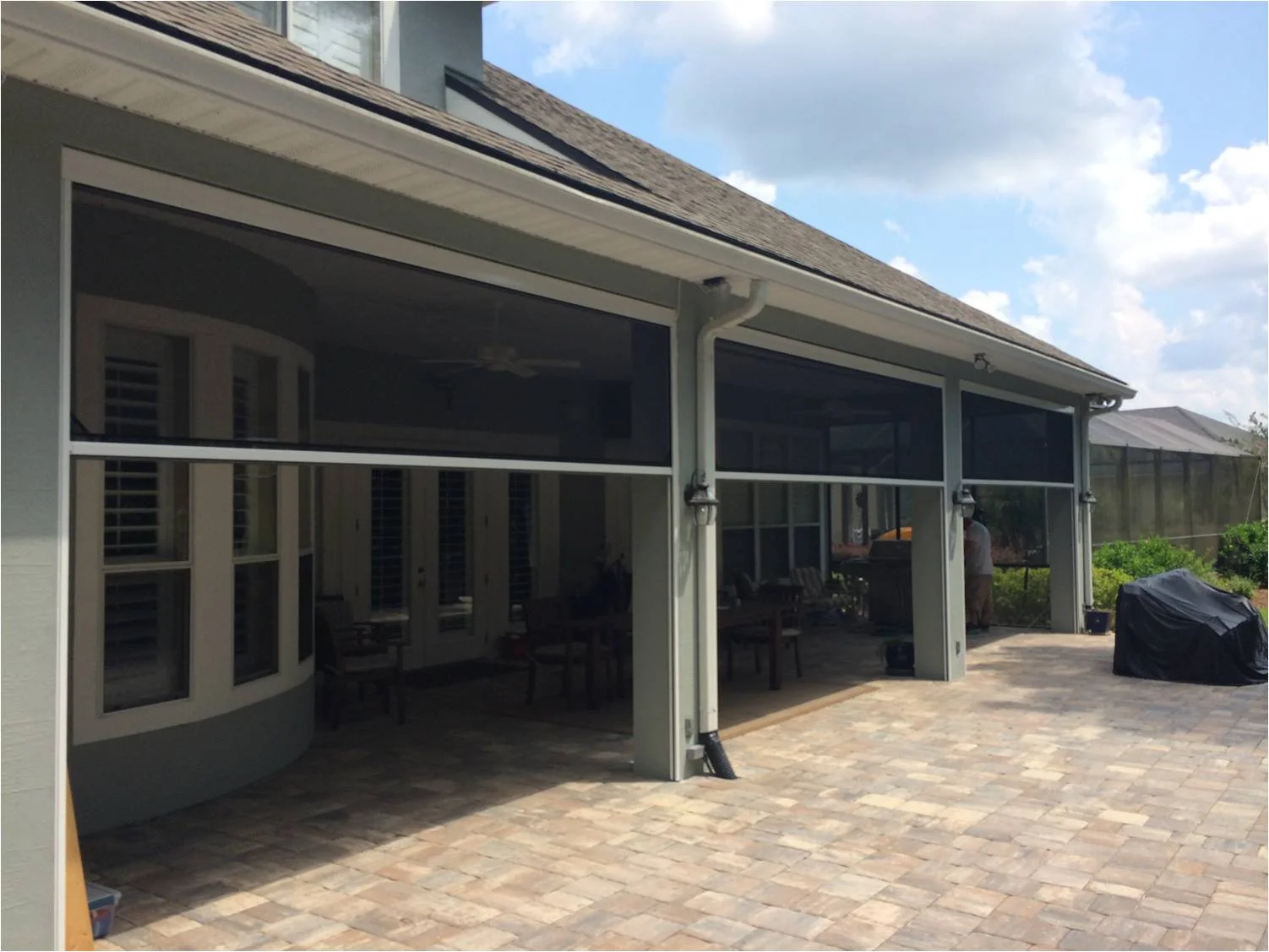 A Sentry retractable screen enclosing a covered outdoor living area on a Minnesota home