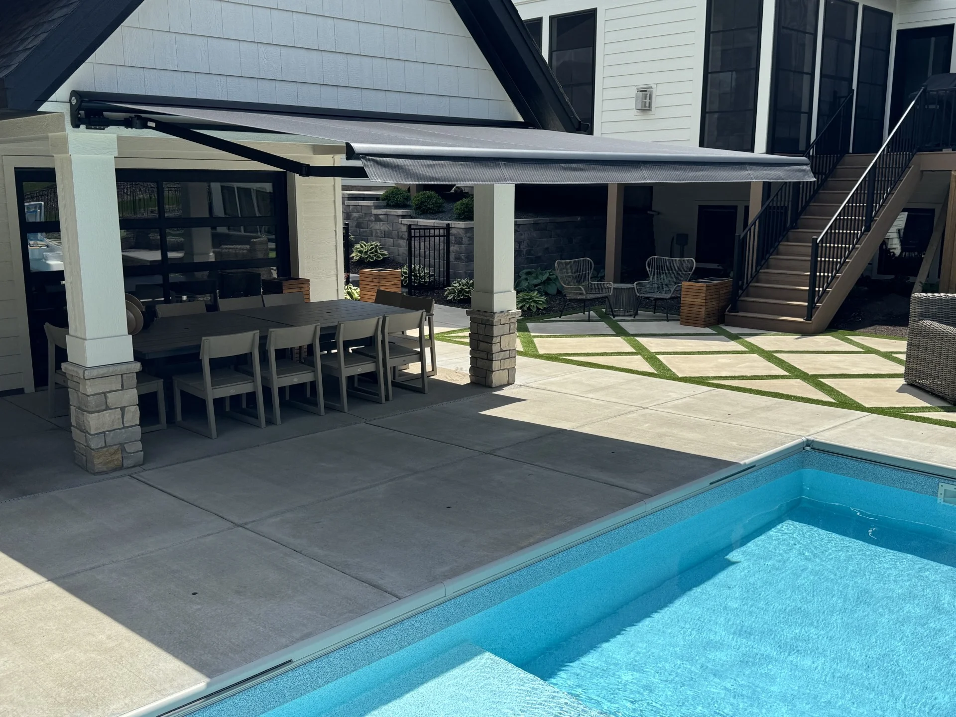 A motorized Sunesta retractable patio awning with a black SmartCase cassette shading a poolside patio in Otsego, Minnesota