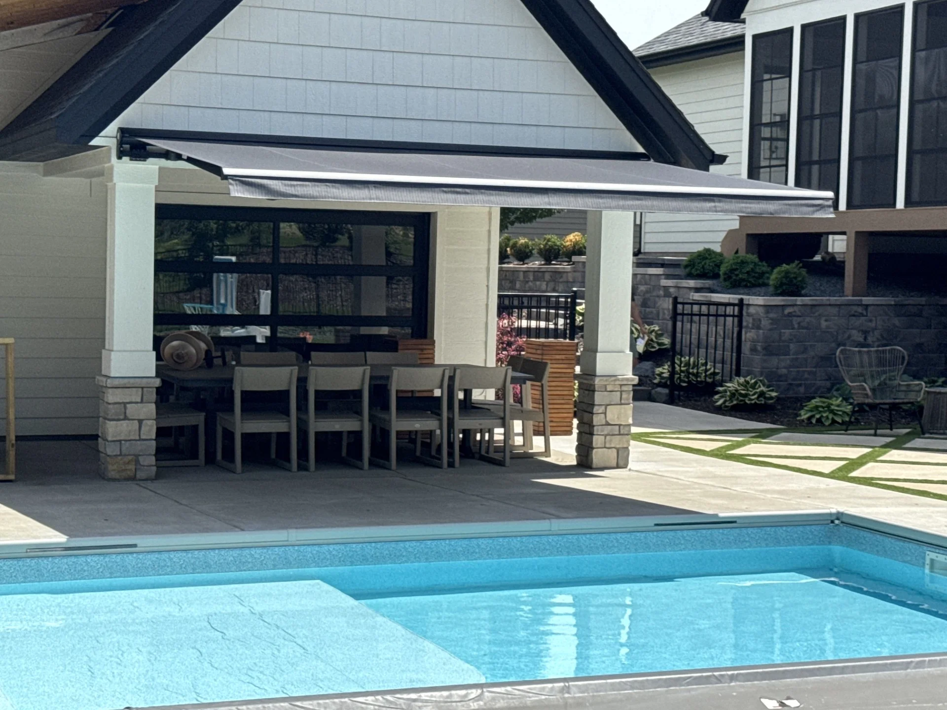 A motorized Sunesta retractable awning with a black SmartCase cassette extended over a poolside patio in Otsego, Minnesota