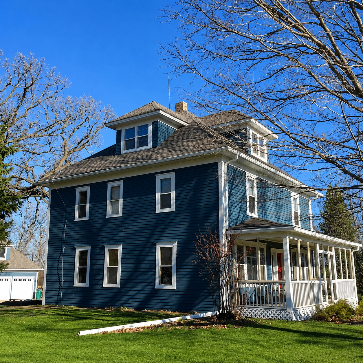 Completed navy blue exterior repaint with bright white trim under a clear sky.