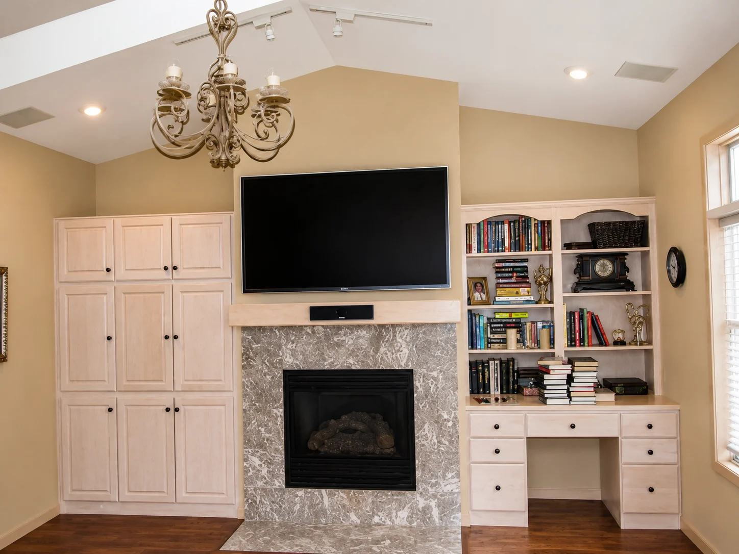 Custom built-in cabinetry and fireplace surround finished in a light painted tone with integrated shelving and desk.