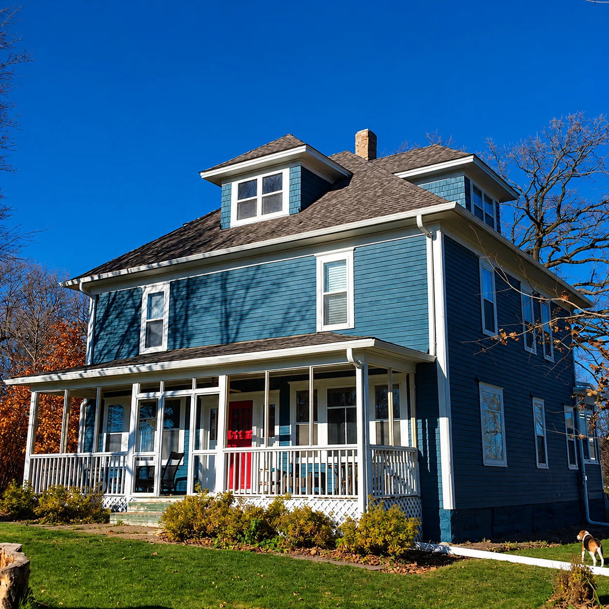 Two-story home freshly painted in deep navy blue with crisp white trim and wraparound porch.