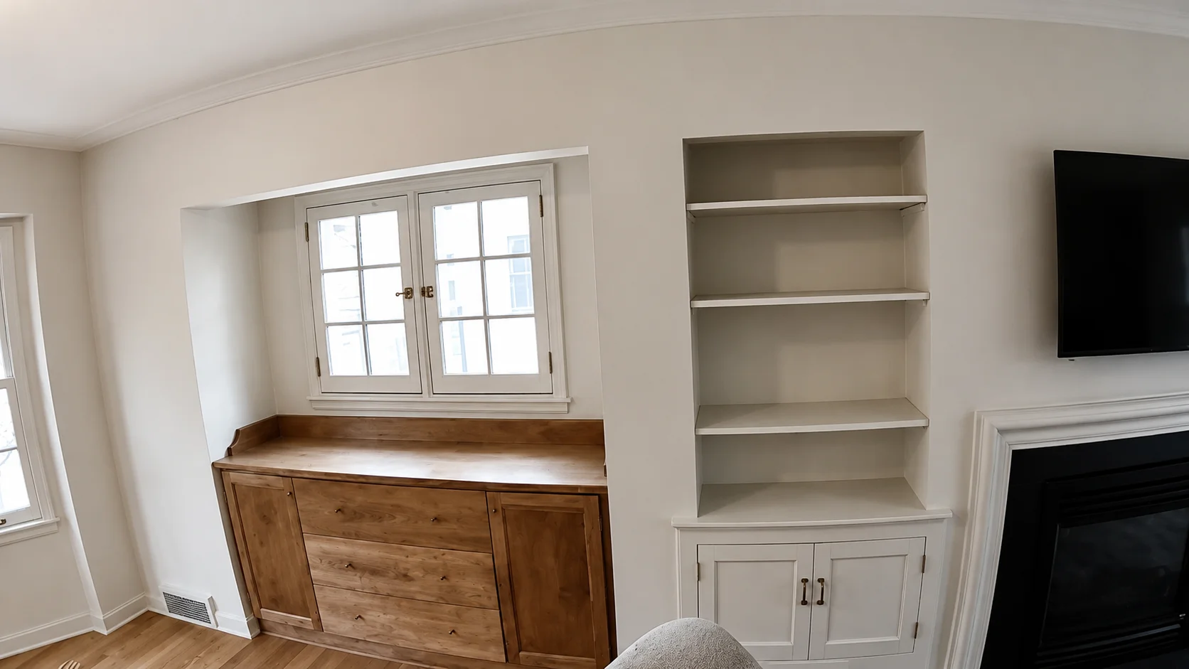 Built-in window bench and shelving painted in a clean neutral finish beside a fireplace.