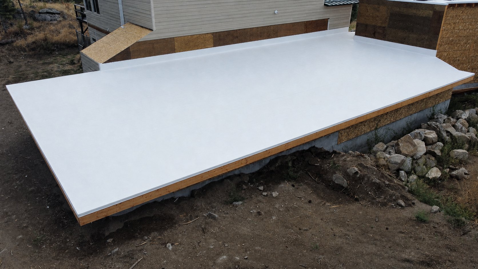 Newly installed white PVC flat roof membrane on a home addition, ready for finish trim.