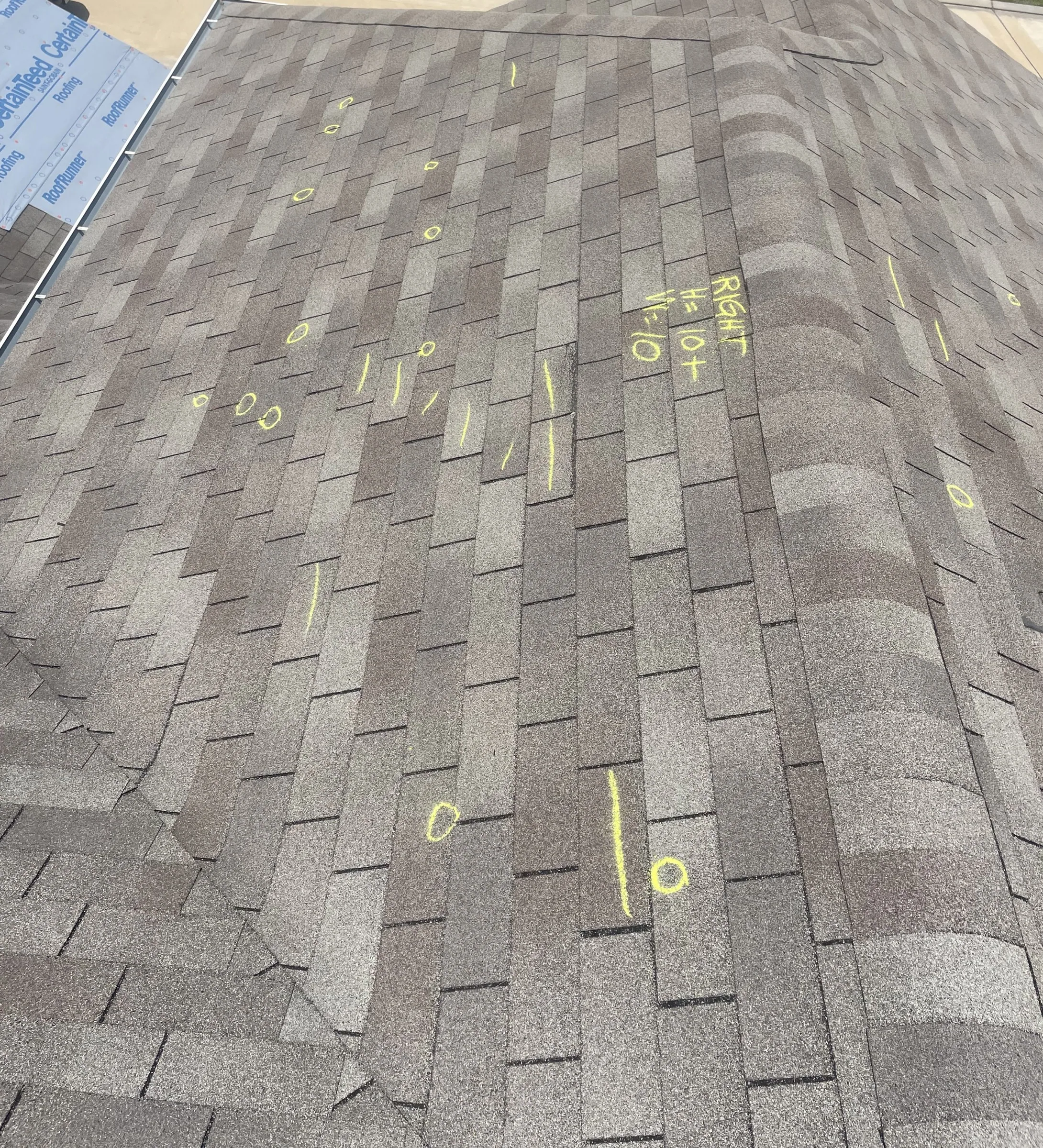 Storm damage to a residential roof with missing shingles during a severe thunderstorm with lightning.