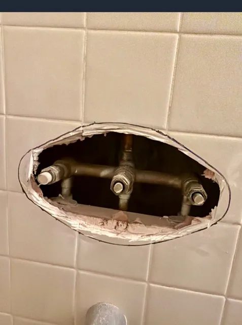 Old three-handle shower and tub valve before replacement