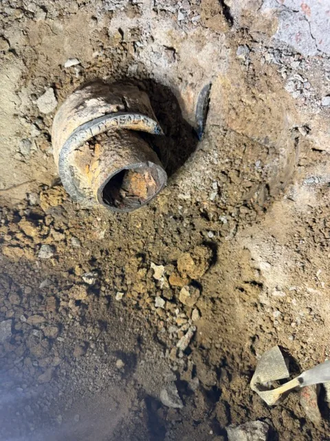 Rotted cast iron floor drain pipe being cut out