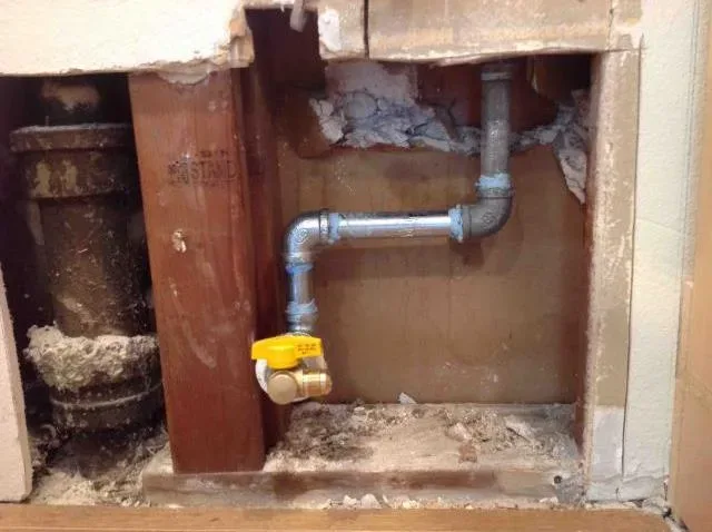 Wall opened for a pipe and valve repair by Graham Plumbing