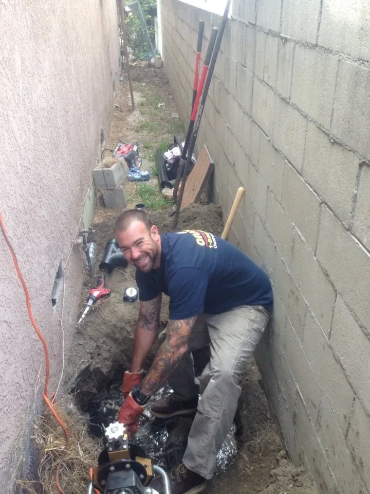 Graham Plumbing plumber working on a line in a trench