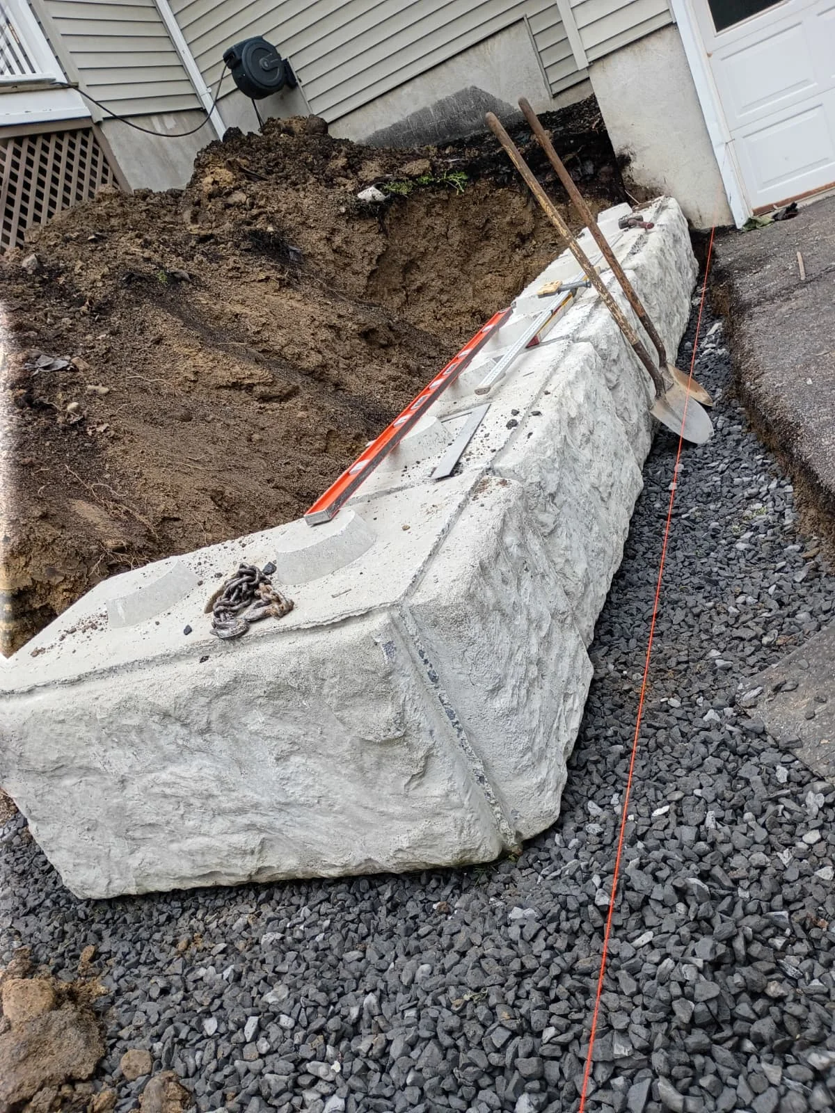Concrete foundation or retaining wall erosion control in progress at a residential construction site.