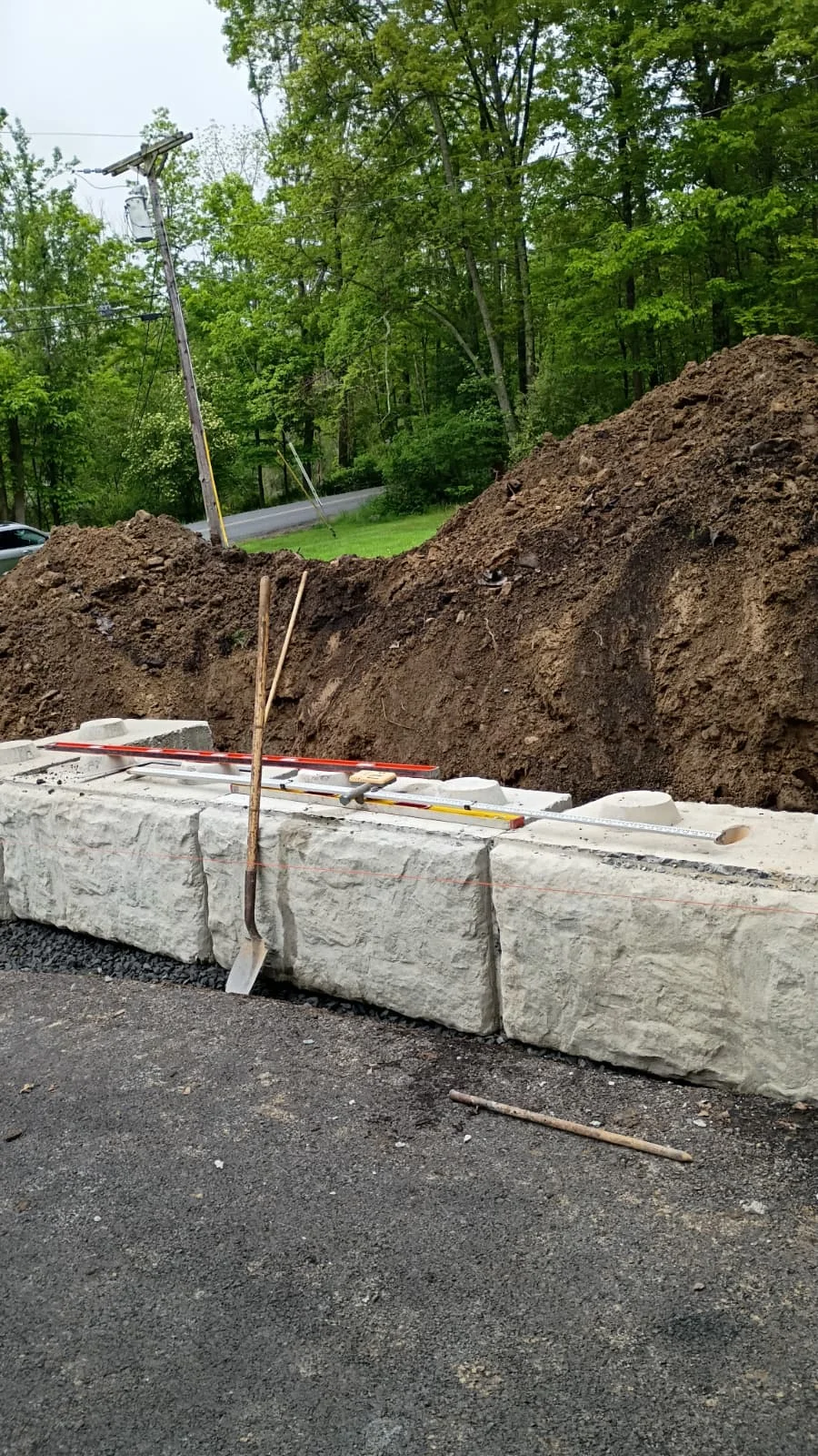 Concrete retaining wall blocks installed during an excavation and foundation project in a residential outdoor setting.