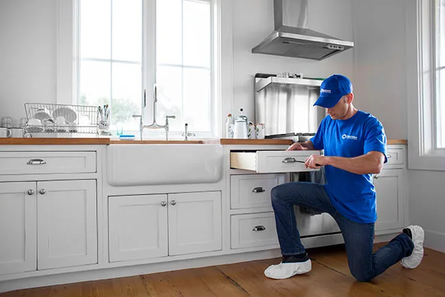 Craftsman working on a dishwasher in a white kitchen
