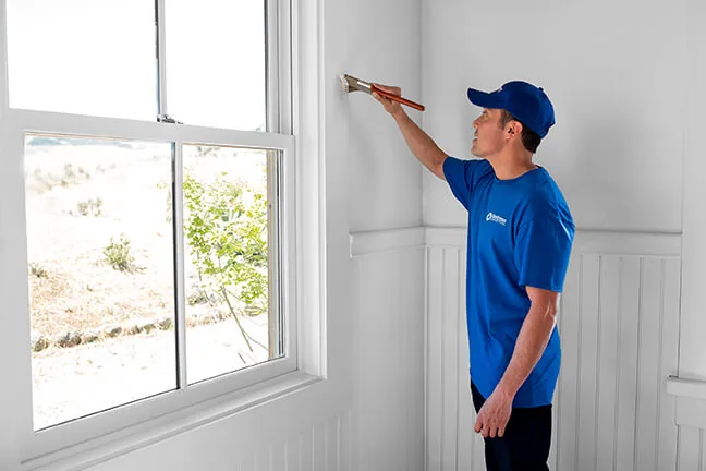Craftsman painting window trim with a brush