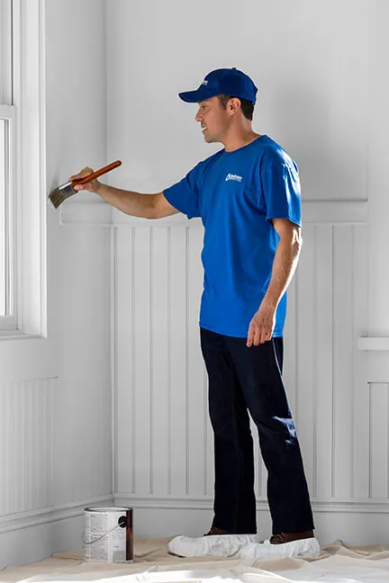 Craftsman brushing paint along a wall