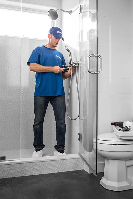 Craftsman working on a shower valve in a glass shower