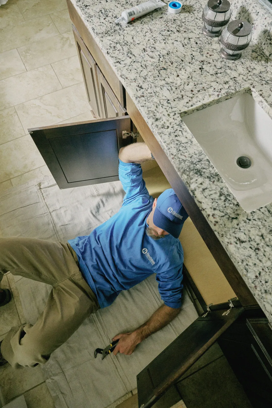 Craftsman working on the plumbing under a bathroom sink