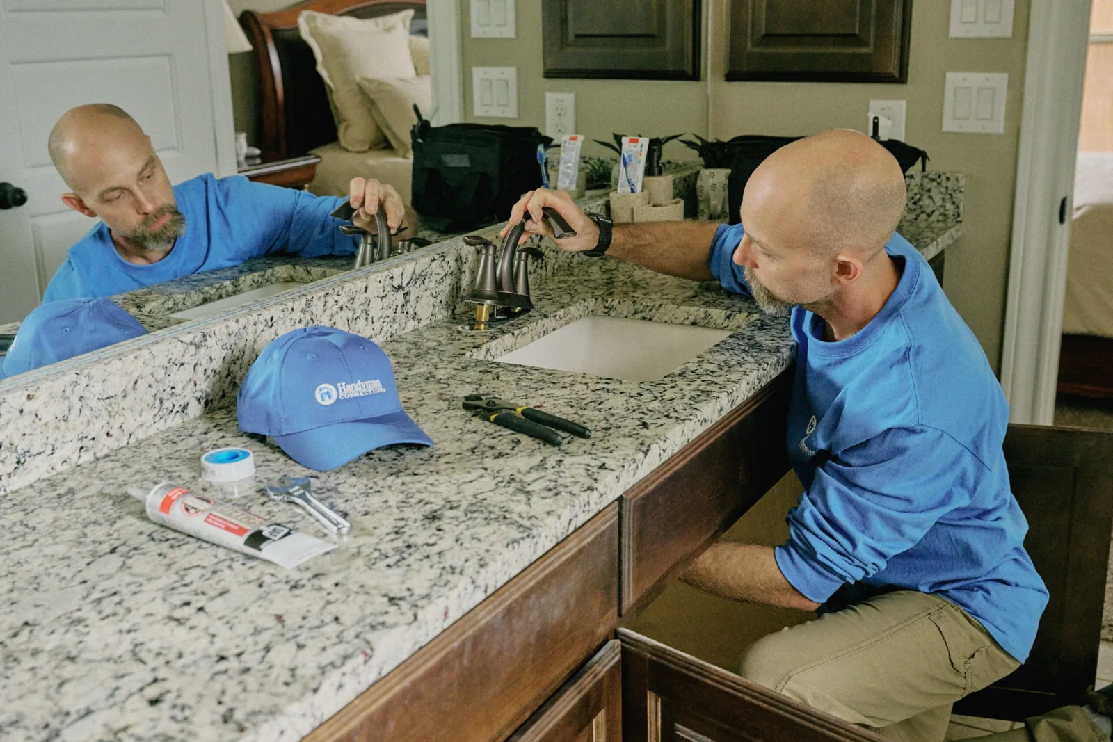 Two craftsmen working on a bathroom vanity with a granite top