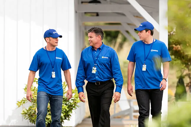 Three Handyman Connection team members walking together outside a home