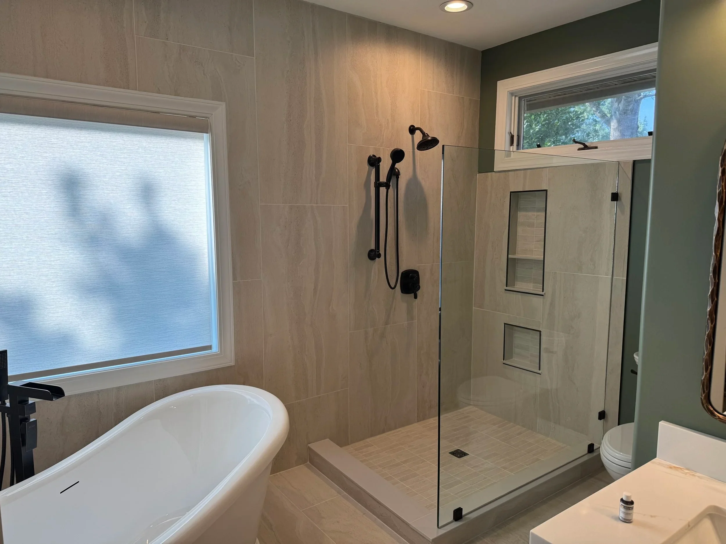 A luxury walk-in shower enclosure with frameless glass doors and rainfall showerhead in a modern bathroom remodel.