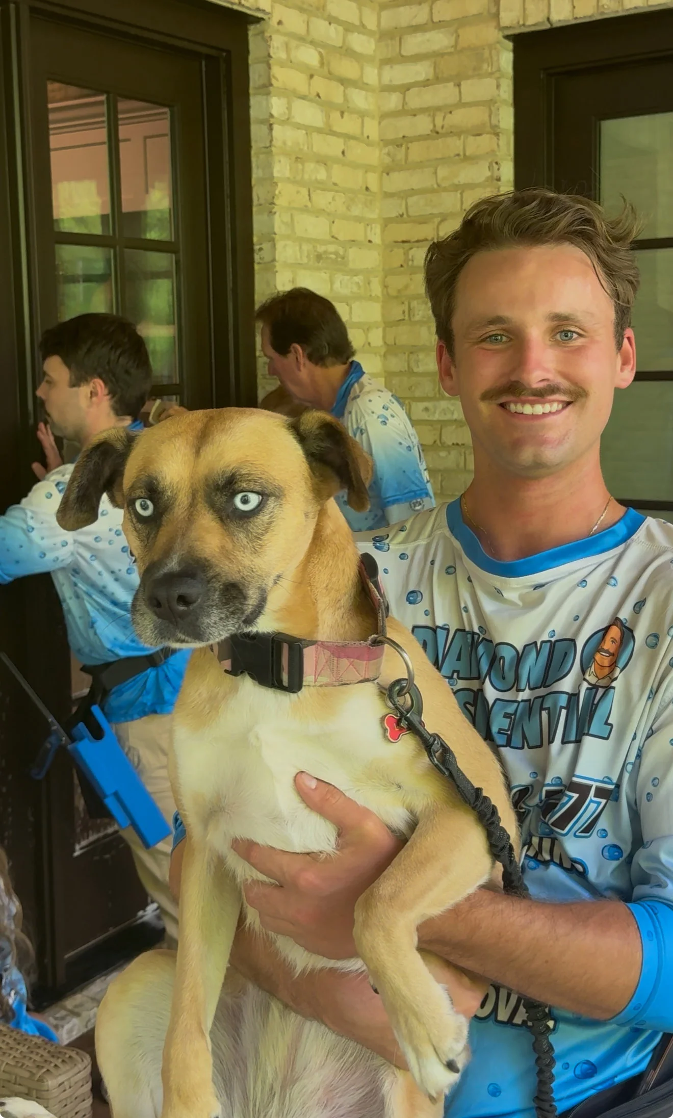 Drew, owner of Diamond Residential, holding a dog while the crew works at a home.