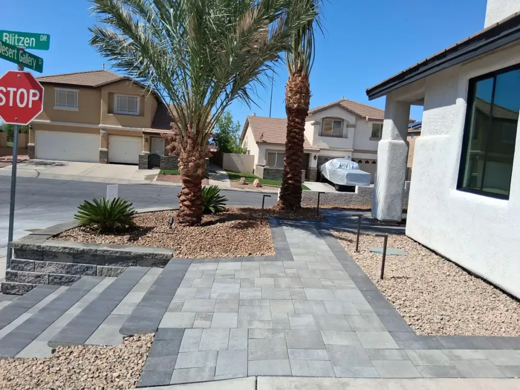 Hardscape patio installation with pavers and desert landscaping in a residential front yard setting.