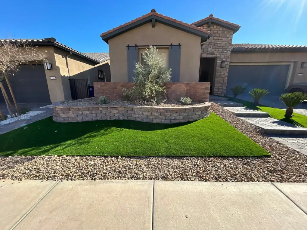 Sod installation and landscape design in a residential front yard featuring freshly laid turf, decorative rock borders, and ornamental plantings.