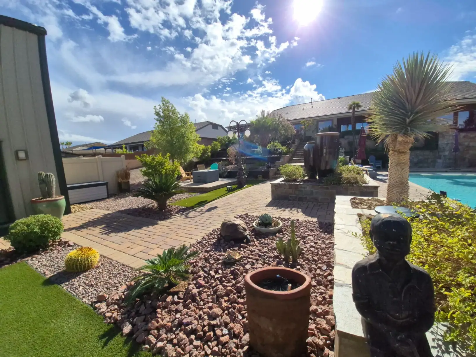 Desert landscaping with decorative hardscape, xeriscaping, and poolside patio in a residential backyard setting.