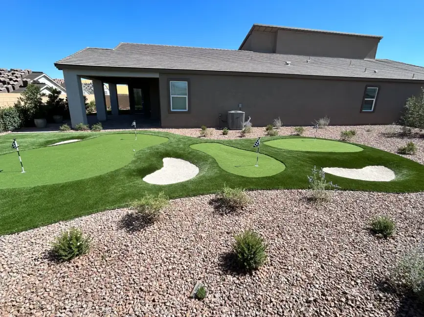 Residential putting green with sand bunkers installed in a backyard landscape setting.