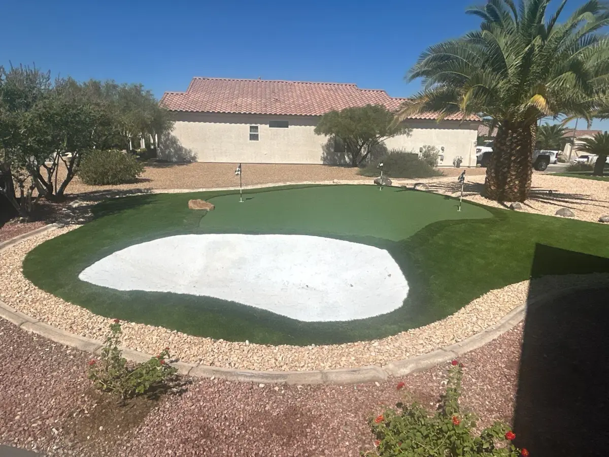 Artificial turf installation with a sand bunker and putting greens in a residential backyard setting.