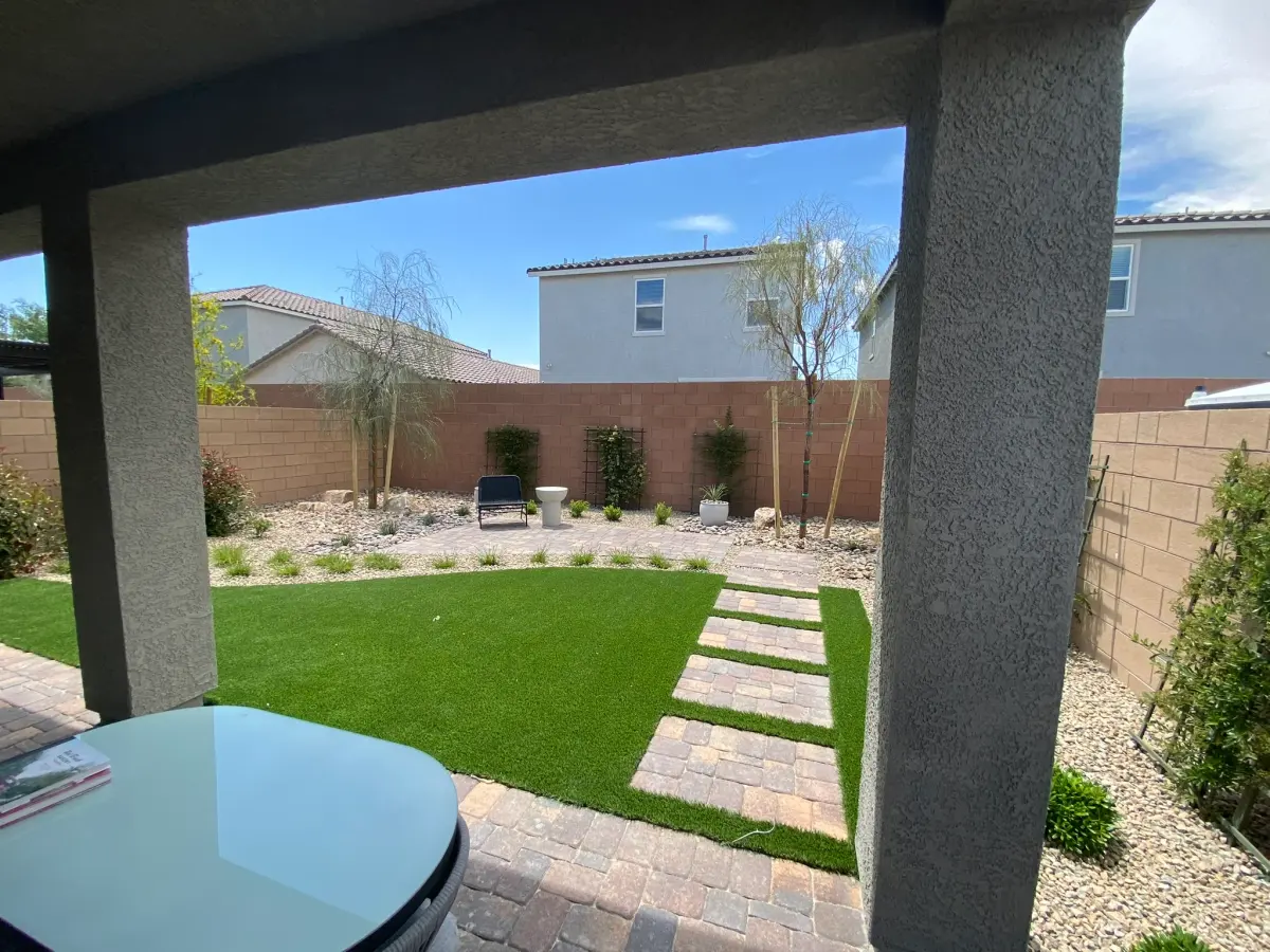 Residential lawn and landscape design featuring artificial turf, hardscape pathways, and xeriscaping in a modern backyard setting.