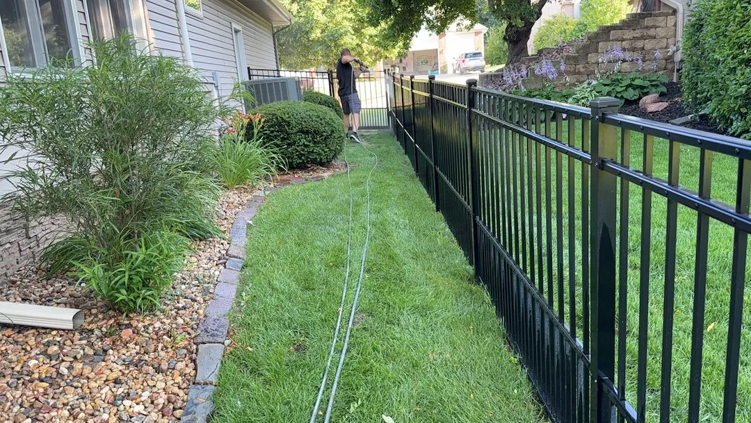 Mowed and edged side yard along a black iron fence