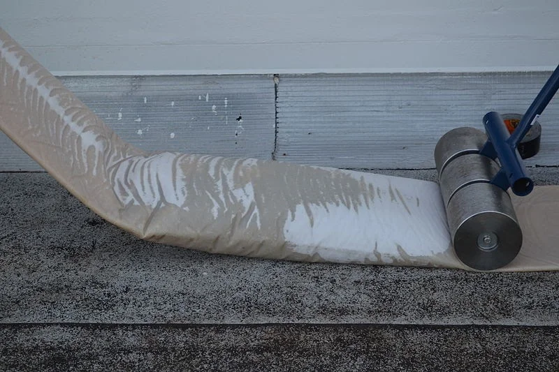 A flexible drainage or ventilation duct laid out on a flat roof surface during installation work.