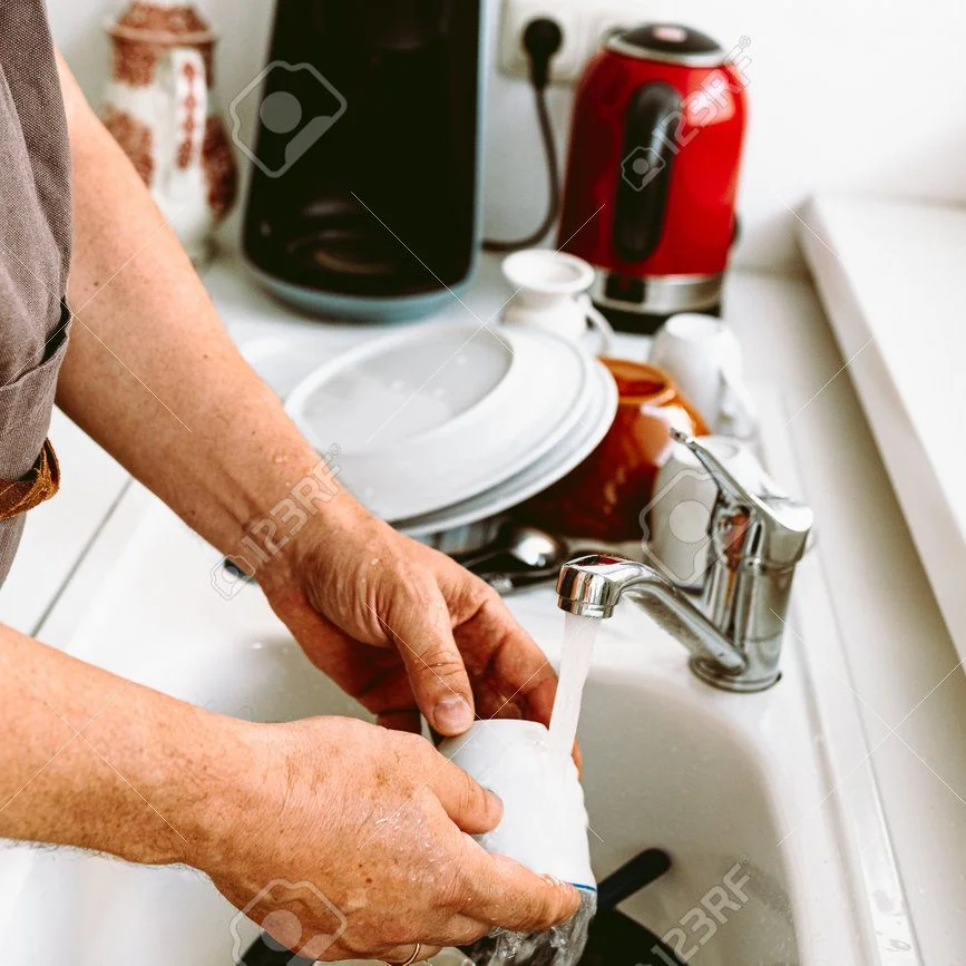 A kitchen sink faucet repair or installation in progress, with a plumber's hands working on the chrome fixture in a residential kitchen.