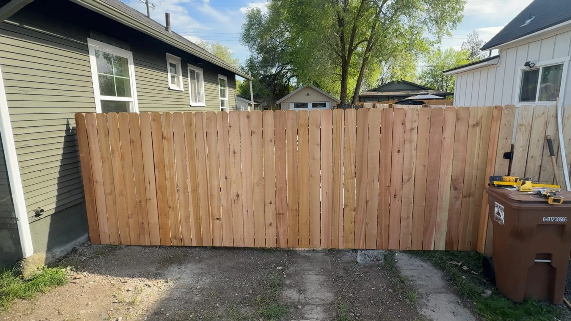 Finished cedar privacy fence installed along a residential property line, with the last panel just hung.