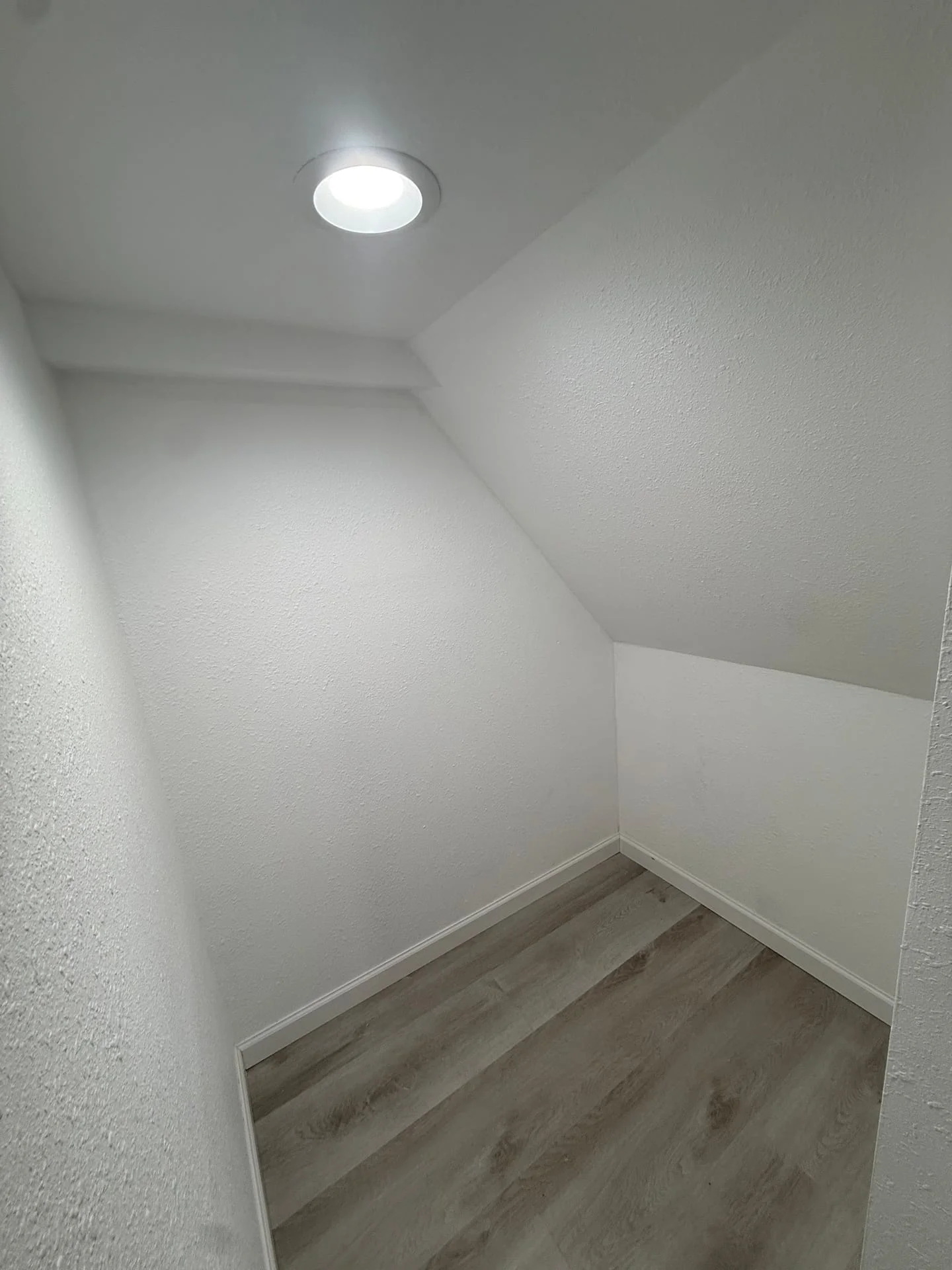 Recessed LED ceiling light fixture installed in a finished interior room with white drywall and wood-look flooring.