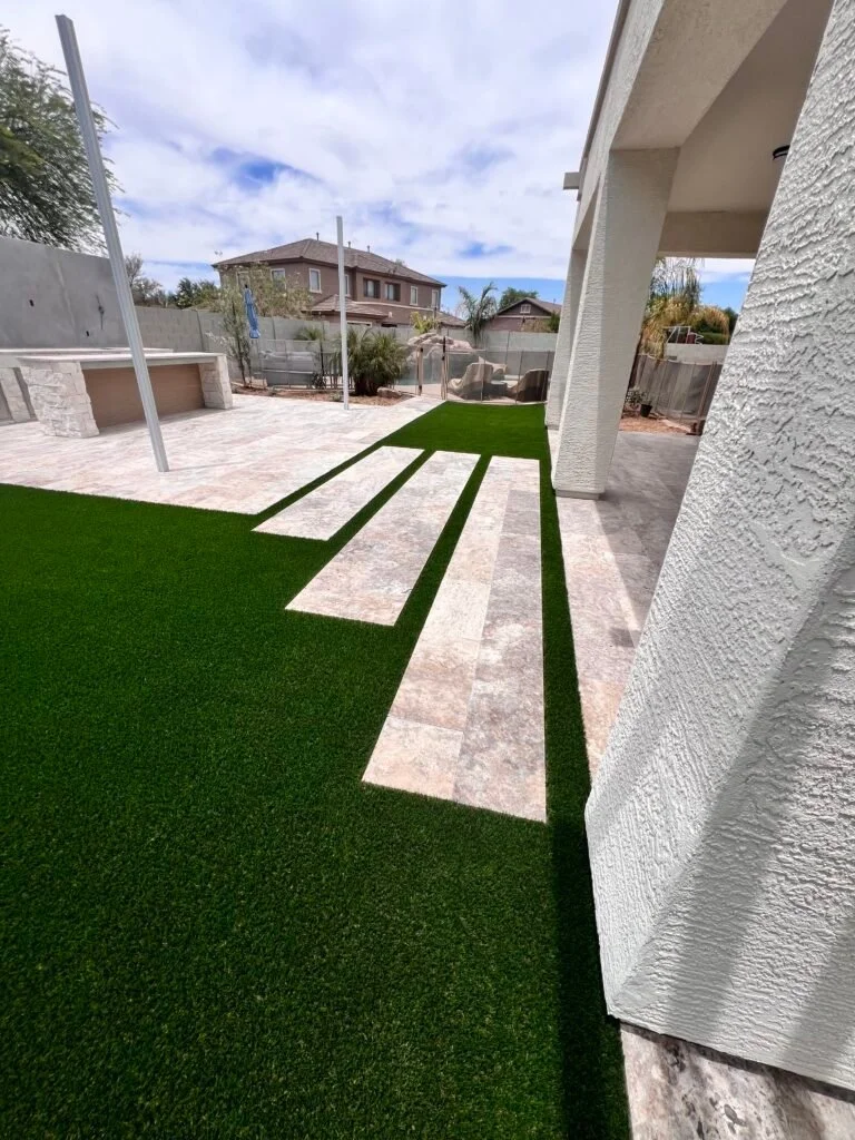 Artificial turf lawn with decorative paver stepping stones in a modern residential backyard.