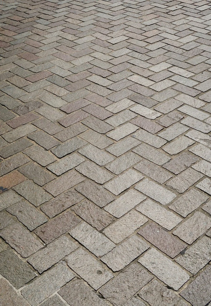 Hardscape patio installation featuring interlocking stone pavers arranged in a herringbone pattern.