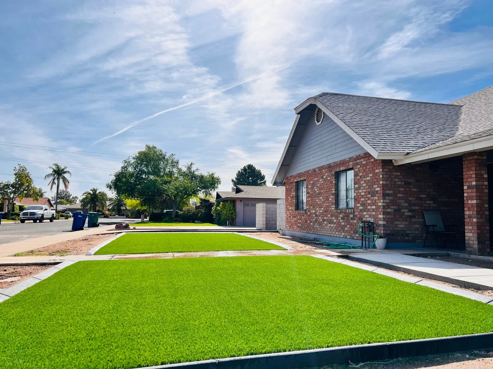 Newly installed sod lawn in front of a brick residential home with concrete edging and mature landscaping.