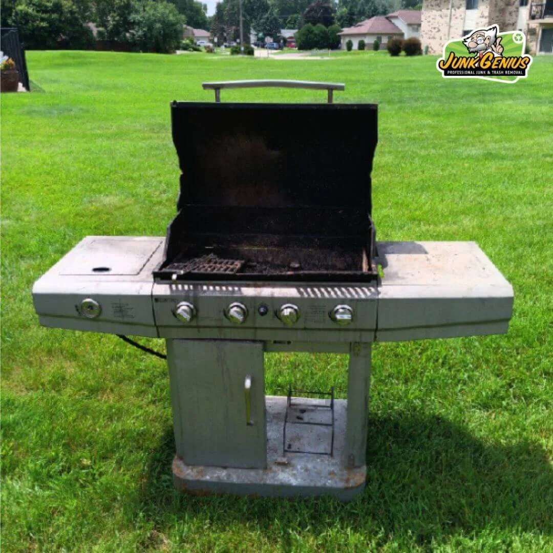 An old gas grill marked for removal sitting in a residential backyard, exemplifying typical junk removal items.