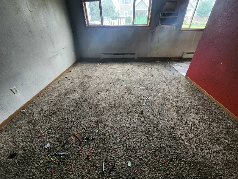 Carpet removal and floor debris in an interior room undergoing junk removal work.