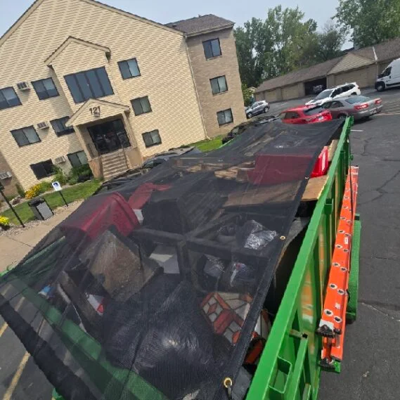 A full dumpster trailer loaded with collected junk and debris in a residential apartment complex parking lot.