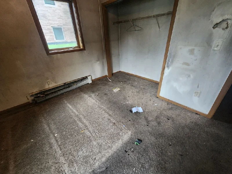 Interior junk removal service shown in an empty residential room being cleared of debris and old carpet.