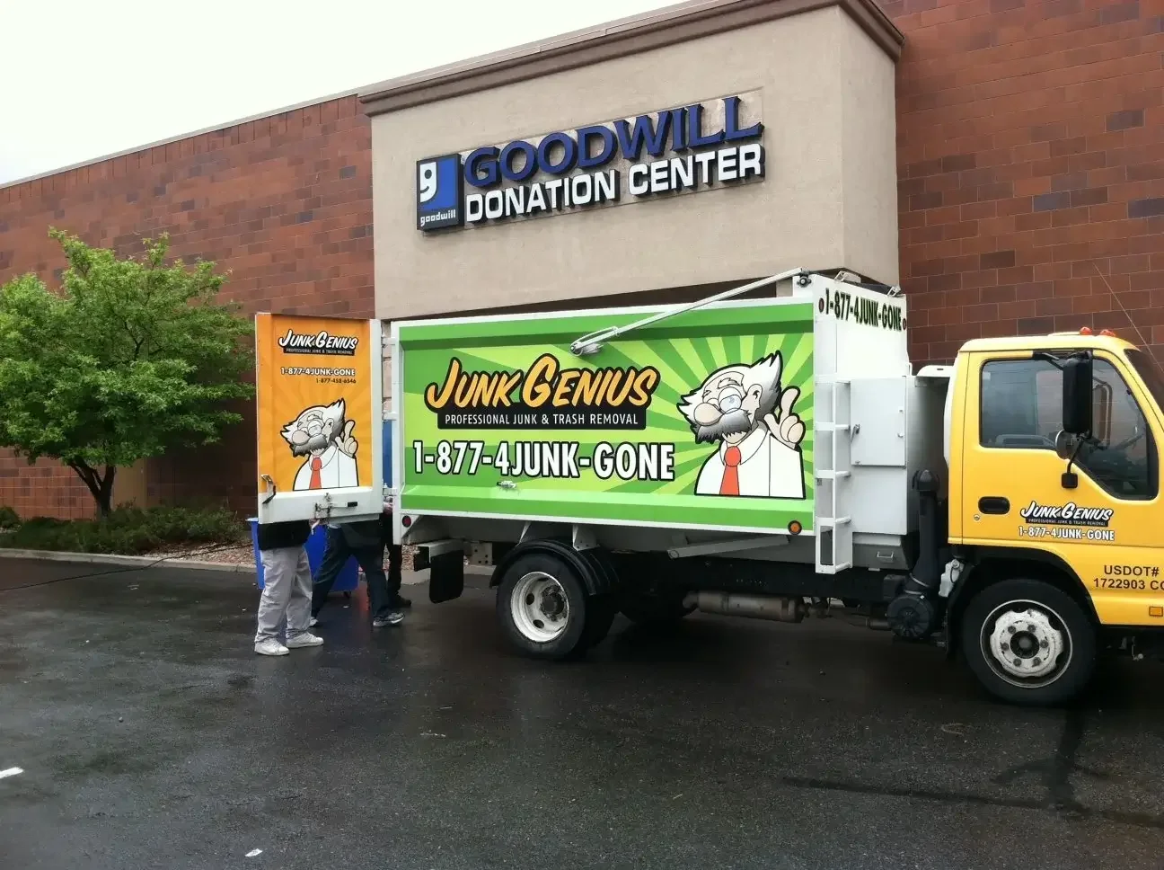 A Junk Genius junk removal truck parked outside a Goodwill Donation Center, displaying the company's branded vehicle and service contact information.
