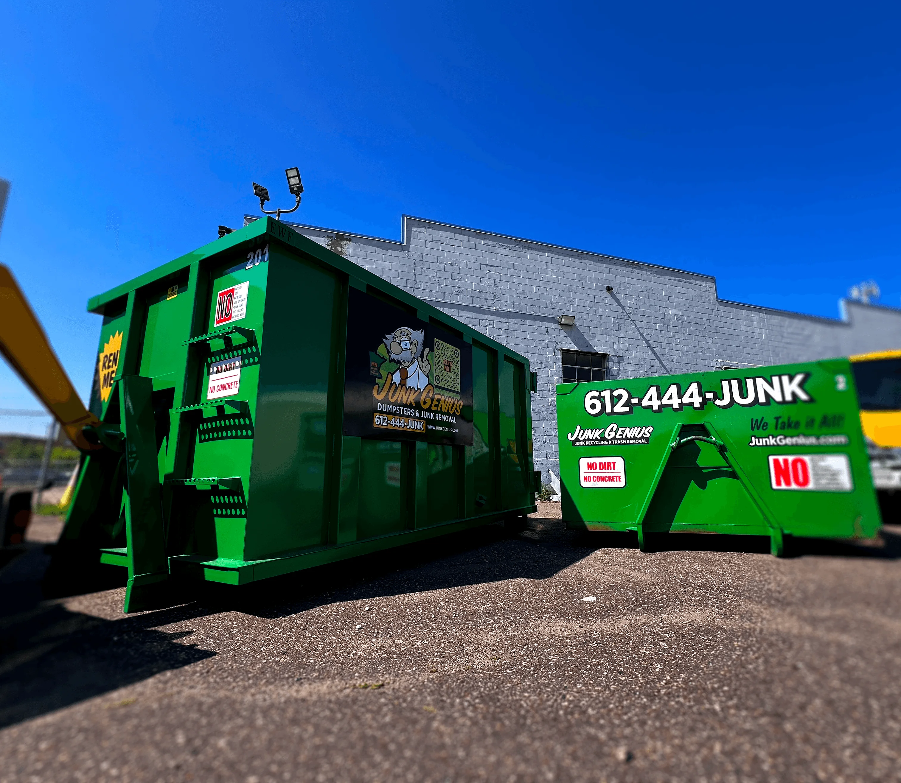 Junk removal dumpsters and service vehicles displayed at a business lot exterior.