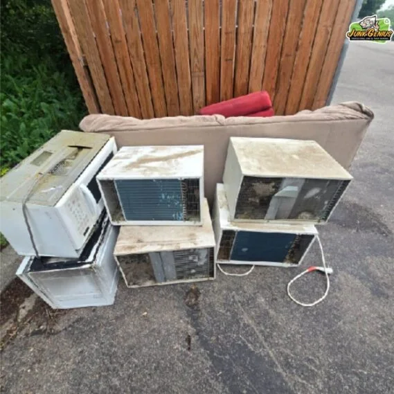 Junk removal service collecting discarded electronic appliances and household items on a residential driveway.