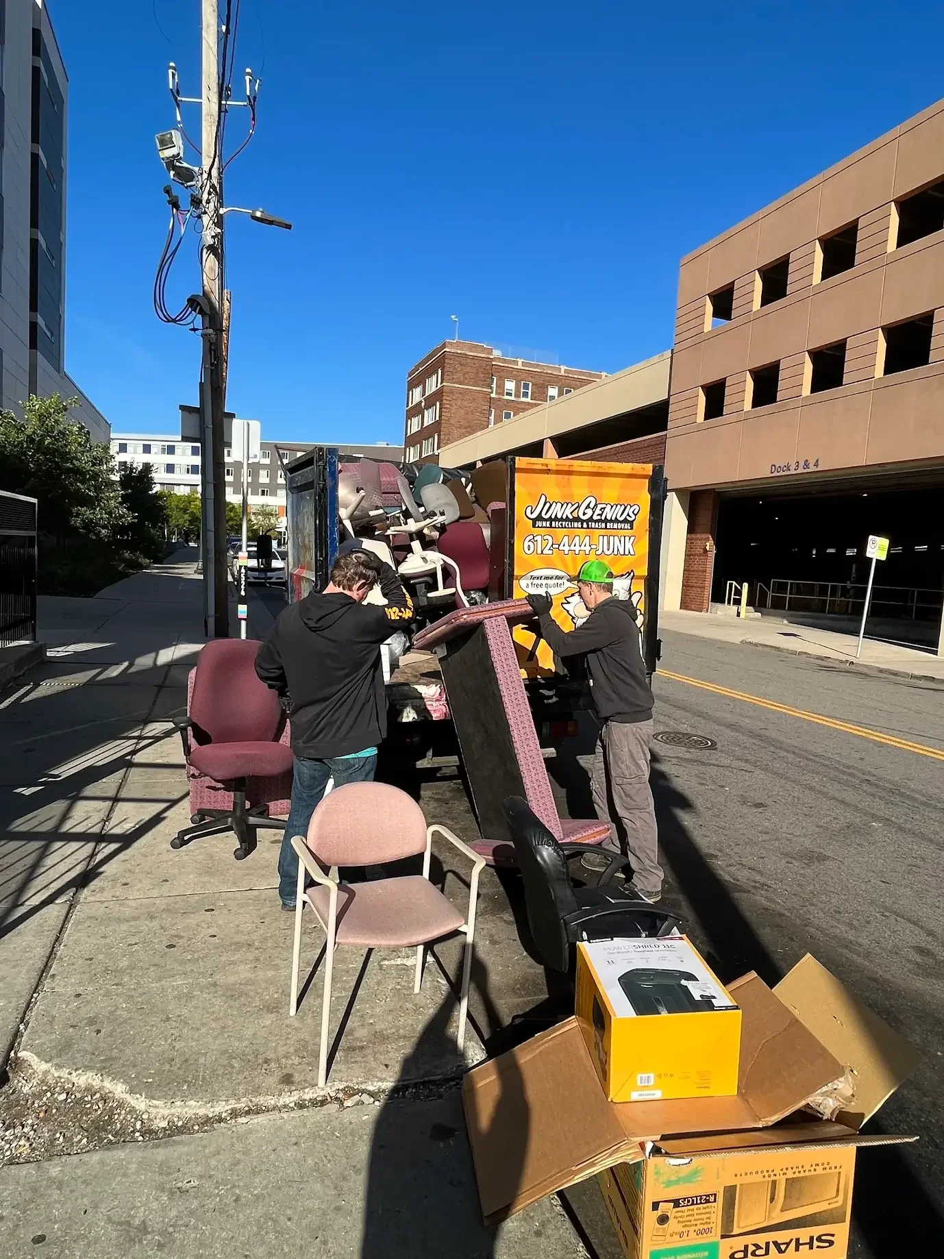 Junk removal service in progress on a city street, with workers loading furniture and items onto a truck.