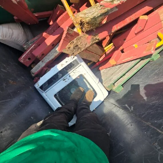 Junk removal service in progress on a ship or barge, with loads of sorted debris and materials being cleared from the vessel's deck.